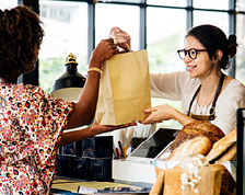 Store clerk smiles as she hands a customer a bag of merchandise.